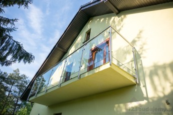 Balkon ze szklaną balustradą z poręczą i słupkami z nierdzewki