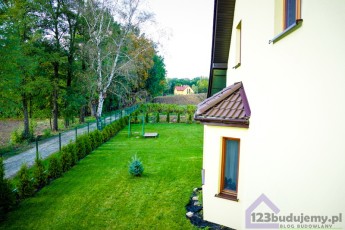 Widok na wykusz, thuje rosną przy ogrodzeniu