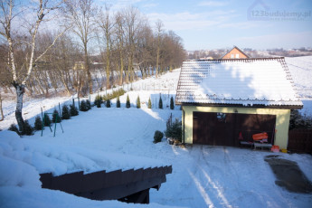 Spadł śnieg, widok na ogród z okna dachowego w sypialni